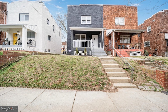 view of front facade featuring a porch, brick siding, and a front lawn