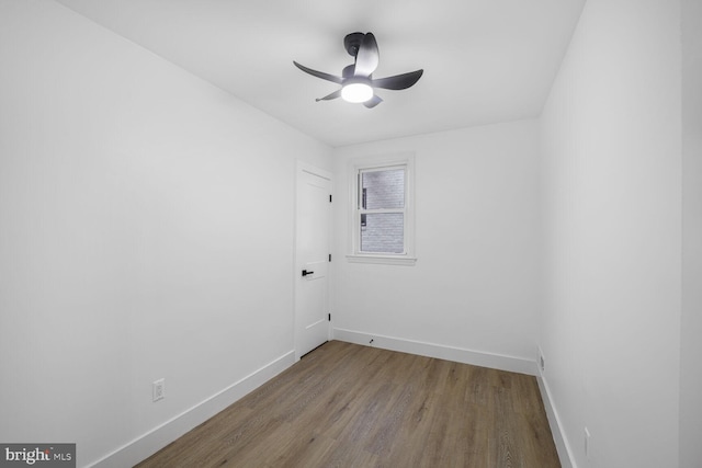 unfurnished room with wood finished floors, a ceiling fan, and baseboards