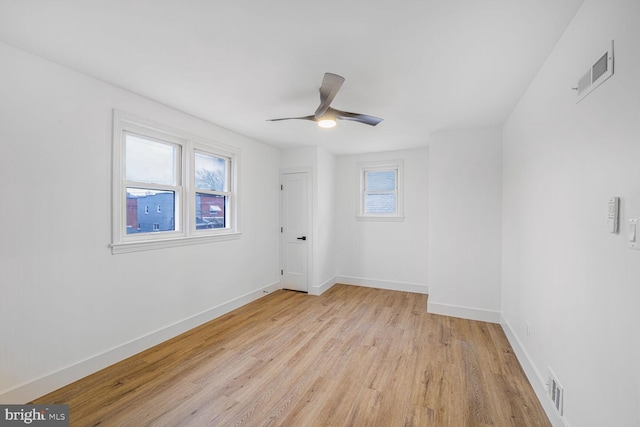 unfurnished room featuring light wood finished floors, visible vents, a ceiling fan, and baseboards