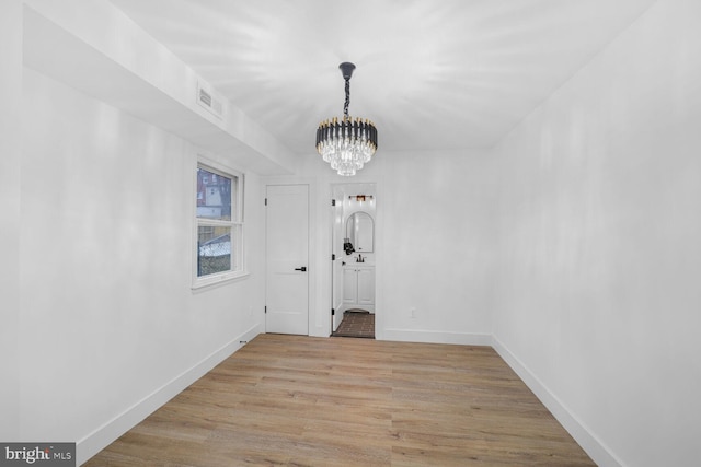 unfurnished dining area featuring a chandelier, visible vents, baseboards, and light wood-style floors