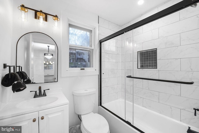 bathroom featuring toilet, vanity, an inviting chandelier, and shower / bath combination with glass door