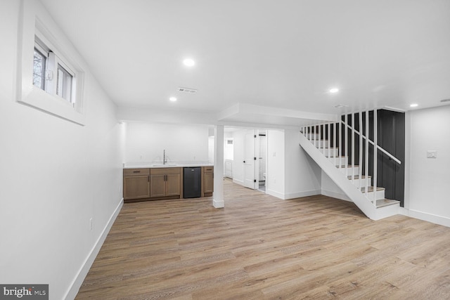 bar with indoor wet bar, stairway, light wood-type flooring, and black dishwasher