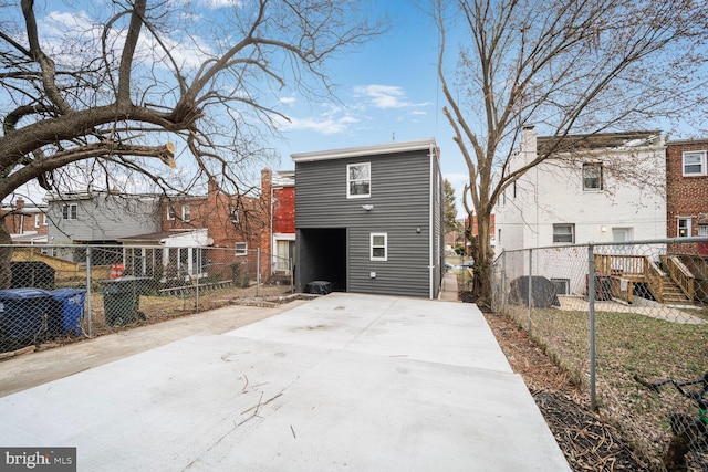 back of property with concrete driveway and fence