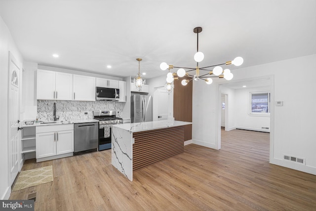 kitchen featuring visible vents, a sink, stainless steel appliances, decorative backsplash, and a chandelier