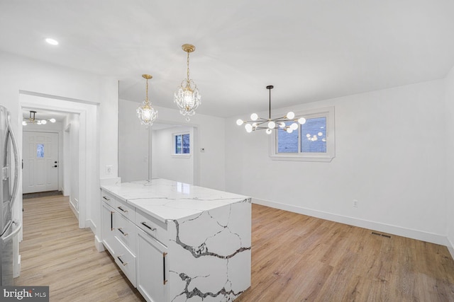 kitchen featuring light wood finished floors, visible vents, hanging light fixtures, a notable chandelier, and white cabinets