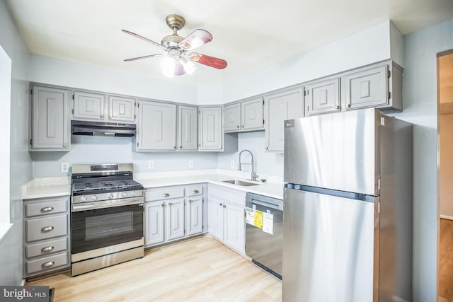 kitchen with under cabinet range hood, gray cabinets, appliances with stainless steel finishes, and a sink