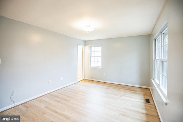 spare room featuring baseboards, visible vents, and light wood-type flooring