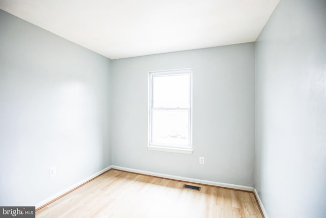 unfurnished room featuring visible vents, baseboards, and wood finished floors