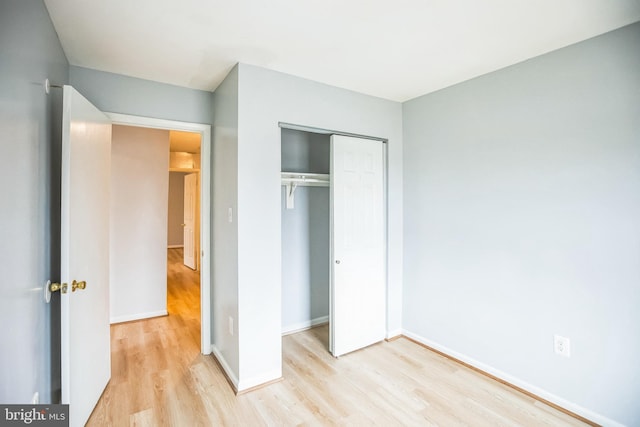 unfurnished bedroom with a closet, baseboards, and light wood-style floors