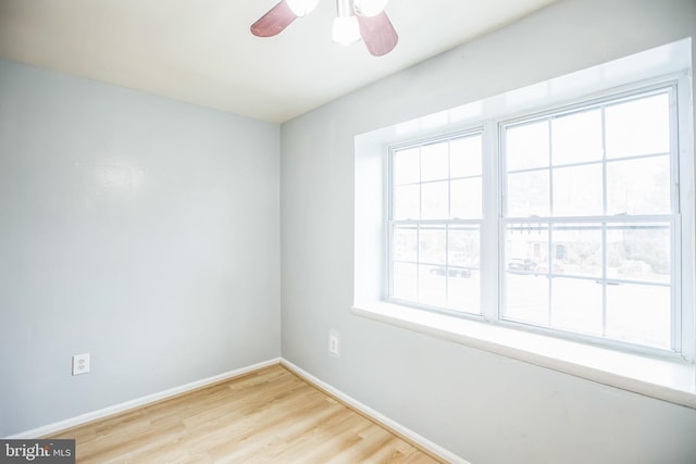 spare room featuring baseboards, wood finished floors, and a ceiling fan