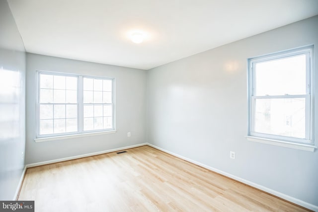 empty room featuring wood finished floors, visible vents, and baseboards