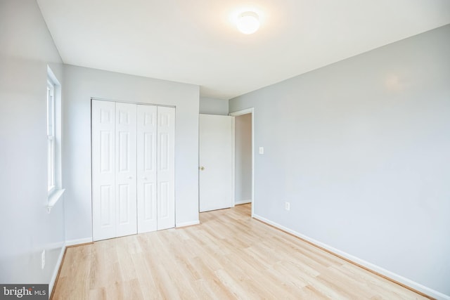 unfurnished bedroom featuring a closet, baseboards, and wood finished floors