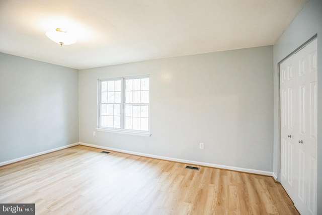 unfurnished bedroom featuring a closet, visible vents, and wood finished floors