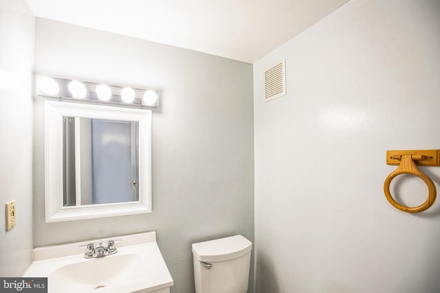 half bath featuring vanity, toilet, and visible vents