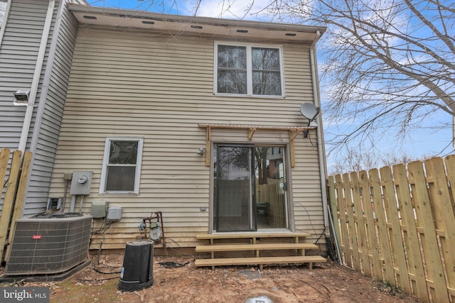 rear view of property with central air condition unit, fence, and entry steps