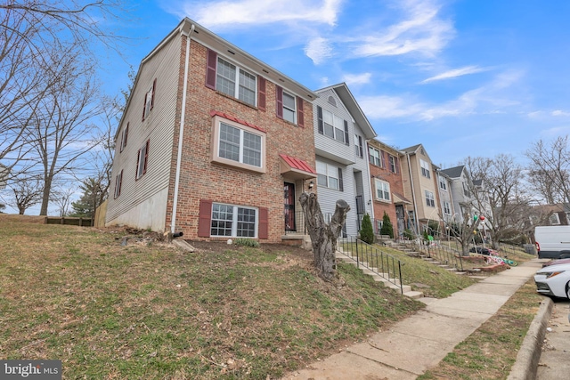 view of front of property with a front yard, brick siding, and a residential view