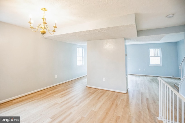 spare room with plenty of natural light, wood finished floors, and a chandelier