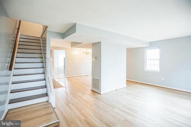 staircase featuring a notable chandelier, wood finished floors, visible vents, and baseboards