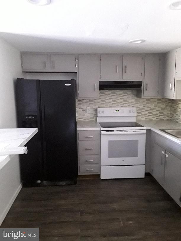 kitchen with white electric stove, gray cabinetry, under cabinet range hood, backsplash, and black refrigerator with ice dispenser