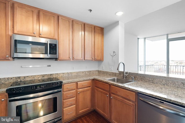 kitchen with a sink, recessed lighting, stainless steel appliances, light stone countertops, and dark wood-style flooring