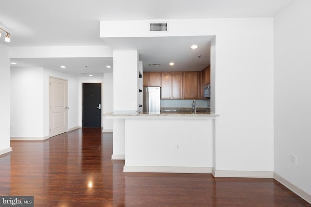 kitchen featuring dark wood finished floors, light stone counters, visible vents, and stainless steel appliances