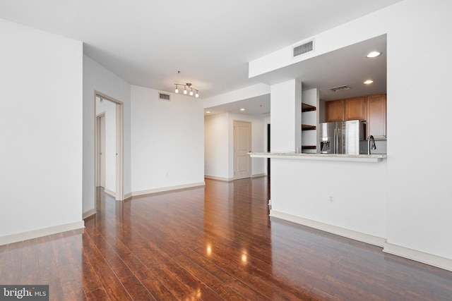 unfurnished living room featuring visible vents, baseboards, and hardwood / wood-style floors