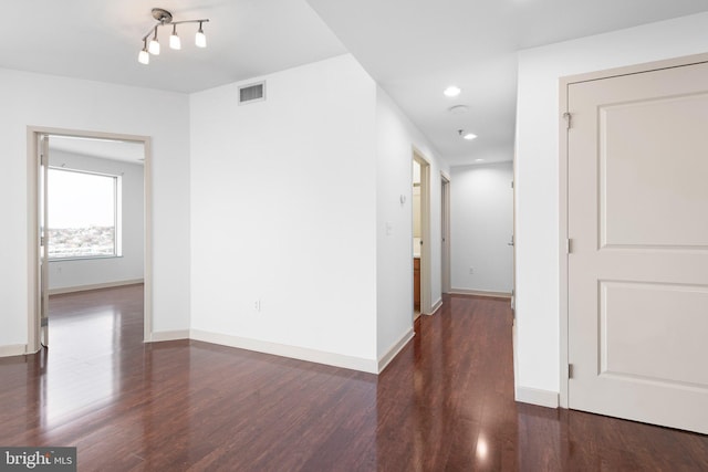 hallway featuring visible vents, baseboards, and wood finished floors