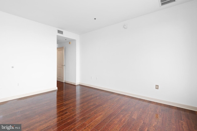 empty room featuring hardwood / wood-style flooring, baseboards, and visible vents