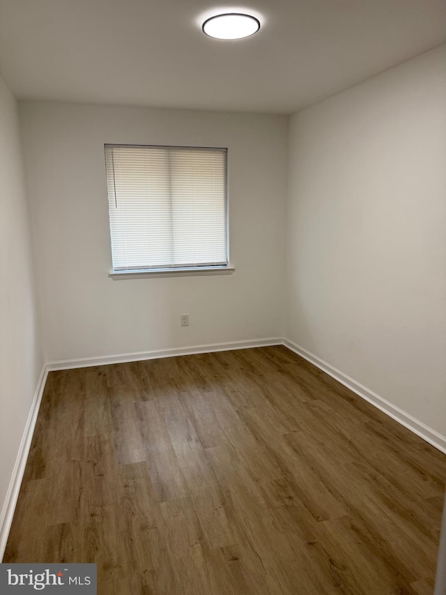 spare room featuring baseboards and wood finished floors