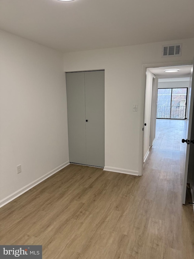 unfurnished bedroom with visible vents, baseboards, a closet, and wood finished floors