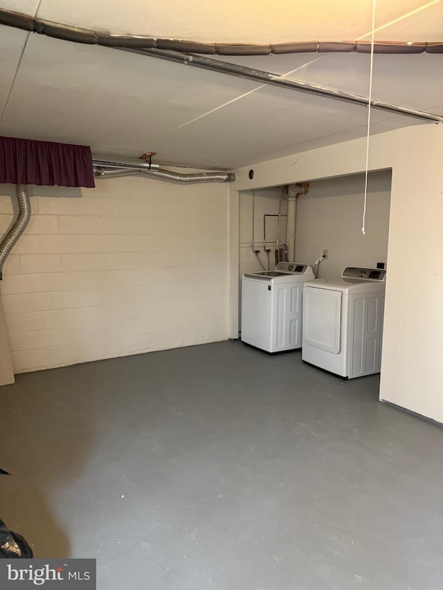 basement featuring concrete block wall and independent washer and dryer