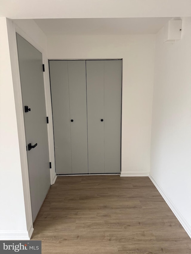 unfurnished bedroom featuring a closet, baseboards, and wood finished floors