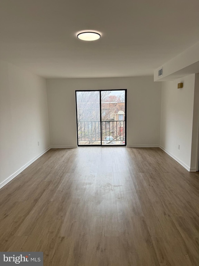 spare room featuring visible vents, baseboards, and wood finished floors