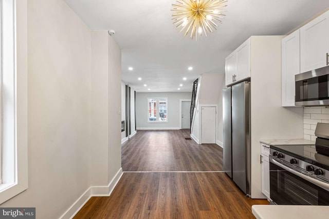 kitchen featuring decorative backsplash, appliances with stainless steel finishes, white cabinets, and dark wood-style floors