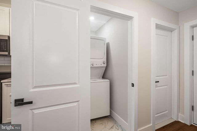 clothes washing area with stacked washer / drying machine, baseboards, and marble finish floor