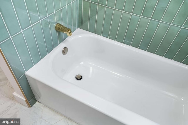 full bath with marble finish floor and a tub to relax in