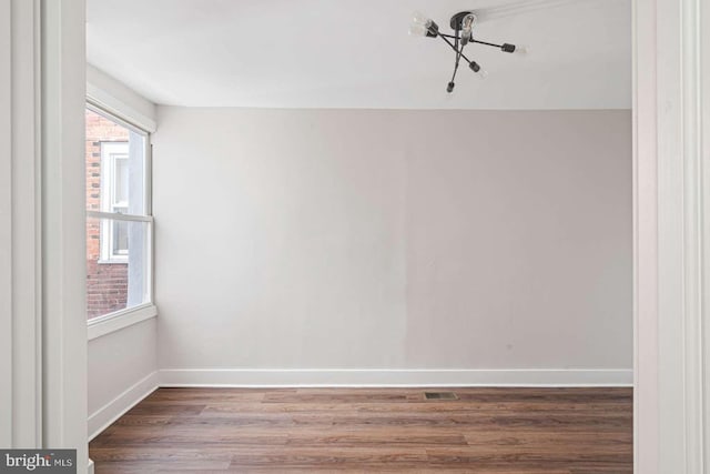 empty room with visible vents, baseboards, and wood finished floors