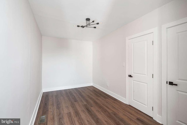 empty room with visible vents, baseboards, and dark wood-style flooring