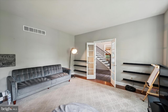 living area with stairway, wood finished floors, visible vents, and baseboards