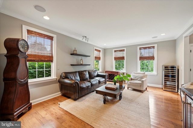 living room featuring wine cooler, a healthy amount of sunlight, crown molding, and light wood finished floors