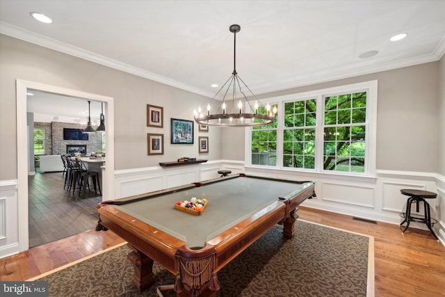 recreation room with an inviting chandelier, visible vents, light wood finished floors, and ornamental molding