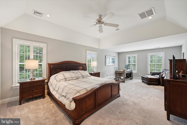 bedroom with a tray ceiling, light colored carpet, visible vents, and baseboards