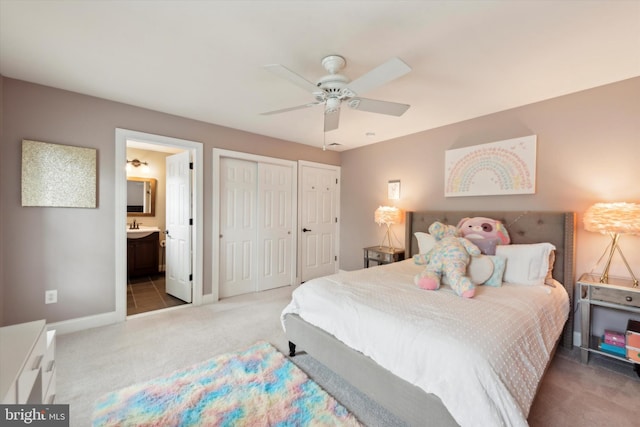 bedroom with ensuite bathroom, a sink, carpet, baseboards, and ceiling fan