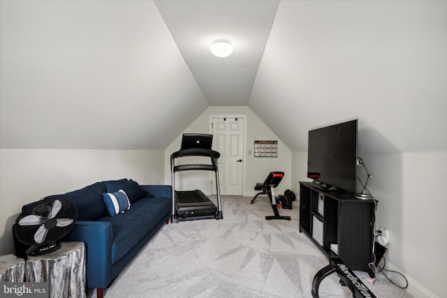 workout room with vaulted ceiling, light colored carpet, and baseboards