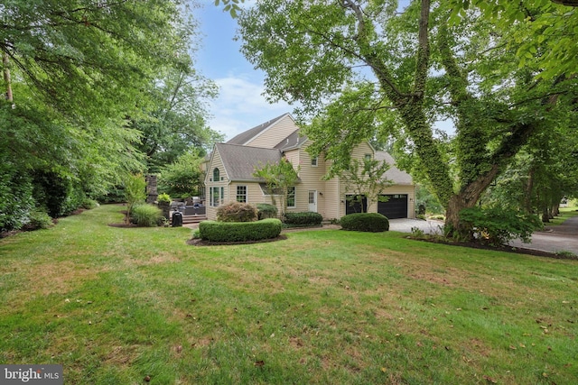 view of front of house featuring a garage, driveway, a shingled roof, and a front yard