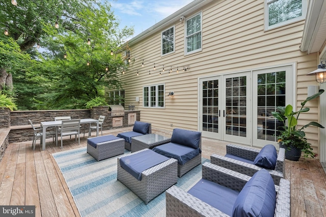 wooden deck with outdoor dining space, exterior kitchen, french doors, grilling area, and an outdoor hangout area