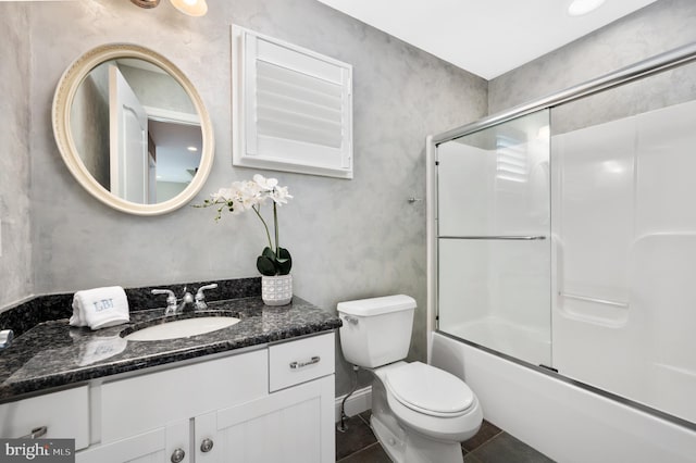 bathroom featuring tile patterned floors, combined bath / shower with glass door, toilet, and vanity