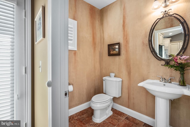 bathroom with baseboards and toilet