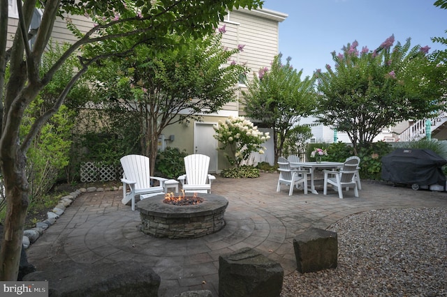 view of patio featuring grilling area, outdoor dining space, an outdoor fire pit, and fence