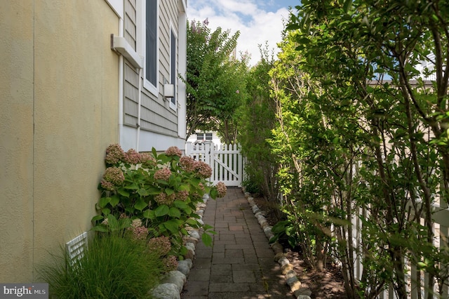 view of home's exterior with stucco siding, fence, and a gate